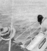 Матрос, отдав шкот, помогает выбрать стаксель-шкот при помощи лебедки. Другой матрос натягивает шкот рукой.