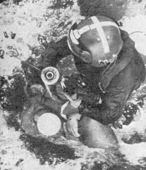 Спасатель готовится поднять пострадавшего, который находится в бессознательном состоянии.